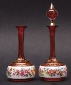 Pair of decorative cranberry glass overlaid scent bottles (one with missing stopper), the bodies