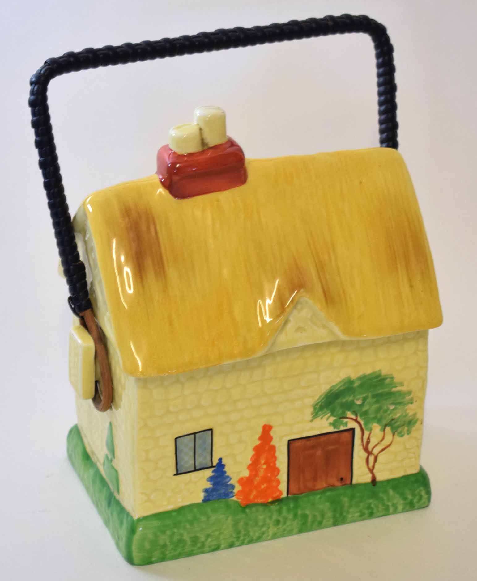Biscuit barrel and cover modelled as a thatched cottage, the barrel with a black basket with handle