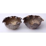 Two various Indian white metal small bowls each with crimped rims and profusely embossed bodies