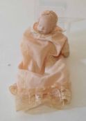 20th century porcelain headed sleeping baby doll in peach coloured christening robes with lace