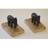 Two patinated base metal paperweights, each modelled in the form of a standing elephant each on a