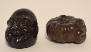 Two carved netsuke, one modelled as a snake coiled within a shell, the other with the face of Buddha