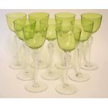 Group of nine wine glasses on tall stems, the bucket shaped bowls with a light green colour, each