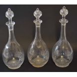 Group of three glass decanters and stoppers of tear drop shape with star cut bases, 32cm high