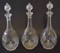 Group of three glass decanters and stoppers of tear drop shape with star cut bases, 32cm high