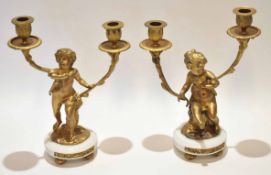 Two gilt metal and white composite two-light candelabra, each modelled in the form of male and