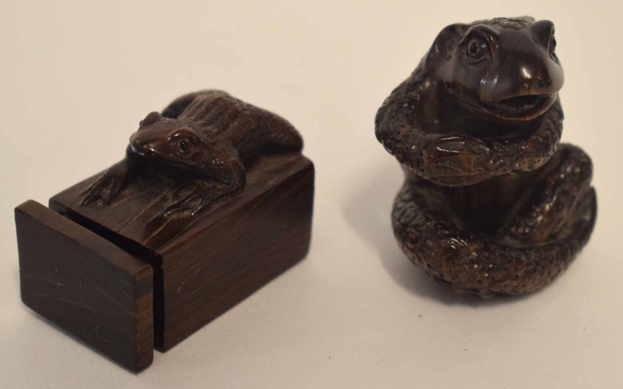 Two wooden netsuke modelled as frogs, one in sitting position, one on a square box