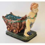 Majolica plant holder modelled as a cherub pulling a cart on rectangular base