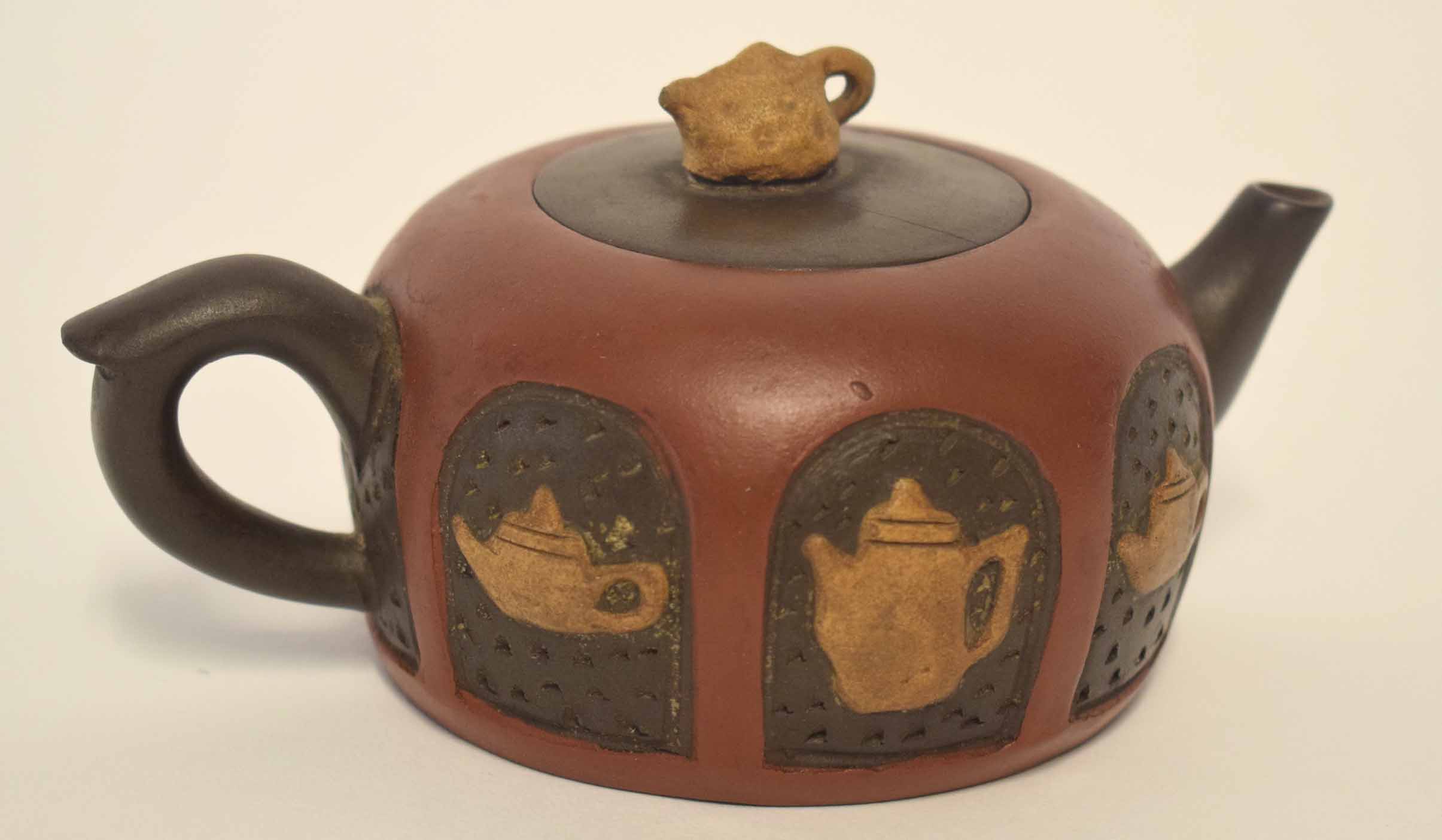 Chinese red ware teapot and cover, the body decorated with tea and coffee pot motifs, the cover with