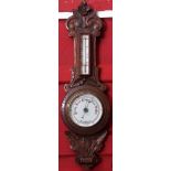 Late 19th century carved oak aneroid wheel barometer, of floral and foliate detail set with a single