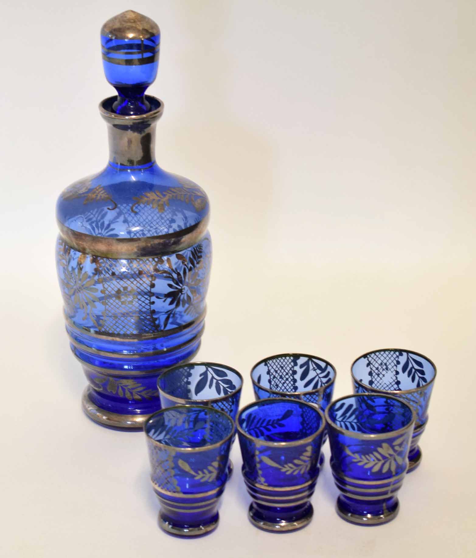 Blue glass decanter with six liqueur glasses, all with a silvered design, decanter 24cm high