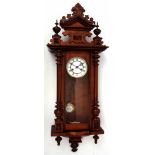 Late 19th century walnut cased Vienna type wall clock, the overhanging cornice with an elaborate