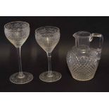 Cut glass water jug together with two wine glasses with engraved design, tallest 19cm