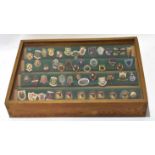 Wooden and glazed fronted case containing 50+ metal and enamelled Bowling Club badges, Norfolk and