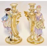 Pair of Continental bisque porcelain candlesticks modelled as lady and a gentleman by a tree on gilt