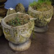 Pair of weathered cement pedestal garden urns of circular form, each moulded with foliate swags,