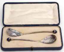 Two George V cased serving spoons each with spot hammered oval bowls, plain stems and basket mounts,