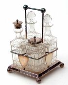 Early 20th century electro-plated four bottle cruet stand of square form with wire work handle,