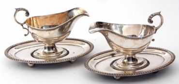 Two early 20th century electro-plated gravy boats, each with integral oval saucer bases and each