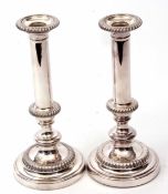 Two silver on copper candlesticks each with detachable nozzles and polished stems with knopped bases