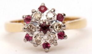 Ruby and diamond cluster ring, the central ruby raised within a surround of small diamonds with a
