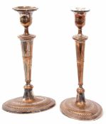 Two silver on copper single candlesticks, each of oval form with urn shaped sconce (one drip pan