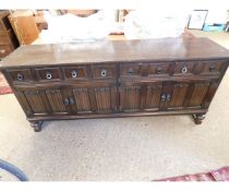 MID-20TH CENTURY OAK FRAMED SIDEBOARD FITTED WITH FOUR DRAWERS OVER FOUR LINEN-FOLD CUPBOARD DOORS