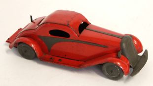 Vintage red tin plate clockwork racing car with plain metal mounts and wheels, stamped "British