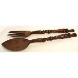 Pair of Eastern softwood over-sized spoon and fork with carved figural handles, 97cm long