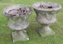 Pair of weathered cement or composition pedestal garden urns, of circular form, the bodies moulded