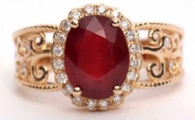 Modern ruby and diamond cluster ring set with an oval cut ruby, 3.10ct (est) within a diamond