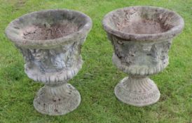 Pair of weathered stone or composition campana shaped pedestal garden urns, each moulded with