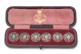 Cased set of six buttons each of pierced circular form with c-scroll and foliate decoration with