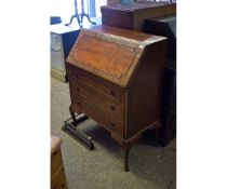 TEAK FRAMED DROP FRONTED BUREAU WITH THREE FULL WIDTH DRAWERS WITH RINGLET HANDLES RAISED ON PAD