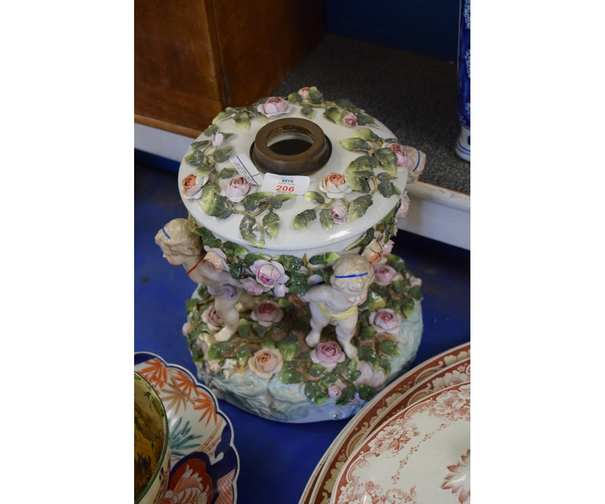 19TH CENTURY CONTINENTAL OIL LAMP WITH FLOWER ENCRUSTED FONT SUPPORTED BY THREE PUTTI WITH CROSSED