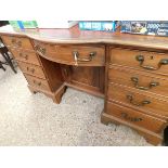 MAHOGANY FRAMED BOW FRONTED LEATHER TOPPED DESK WITH NINE DRAWERS AND ONE CUPBOARD DOOR WITH RED