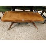 MAHOGANY COFFEE TABLE ON QUATREFOIL BASE WITH BRASS CASTERS