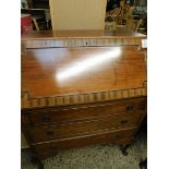 TEAK FRAMED DROP FRONTED BUREAU WITH THREE FULL WIDTH DRAWERS WITH RINGLET HANDLES RAISED ON PAD