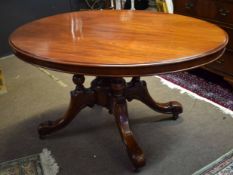 Victorian mahogany oval tilt top dining table with moulded edge over four supports joining a