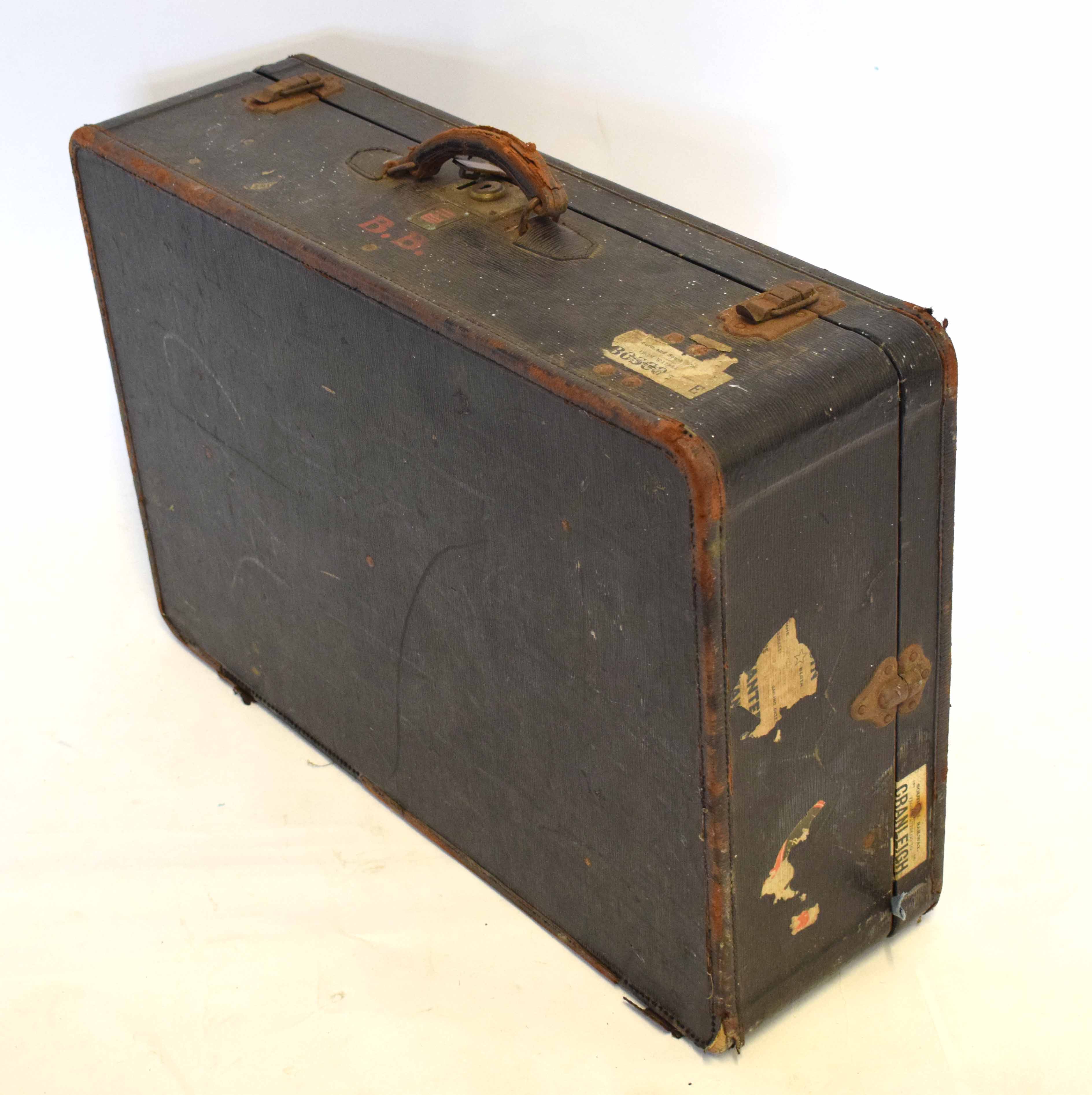 Vintage suitcase with various labels and leather handle with metal fixtures