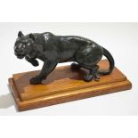 Green spelter model of a stalking tiger on a mahogany stepped plinth, 26cm wide x 16cm tall