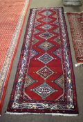 Good quality multi-coloured floor runner with red field and repeating diamond lozenge centre, 83cm