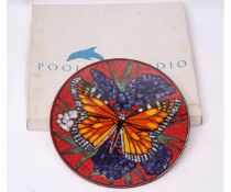 Poole Pottery charger with butterfly design on red ground, the base with factory mark, limited