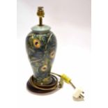 Modern Moorcroft lamp base with a peacock feather style design tube lined in green seated on a