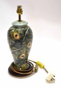 Modern Moorcroft lamp base with a peacock feather style design tube lined in green seated on a