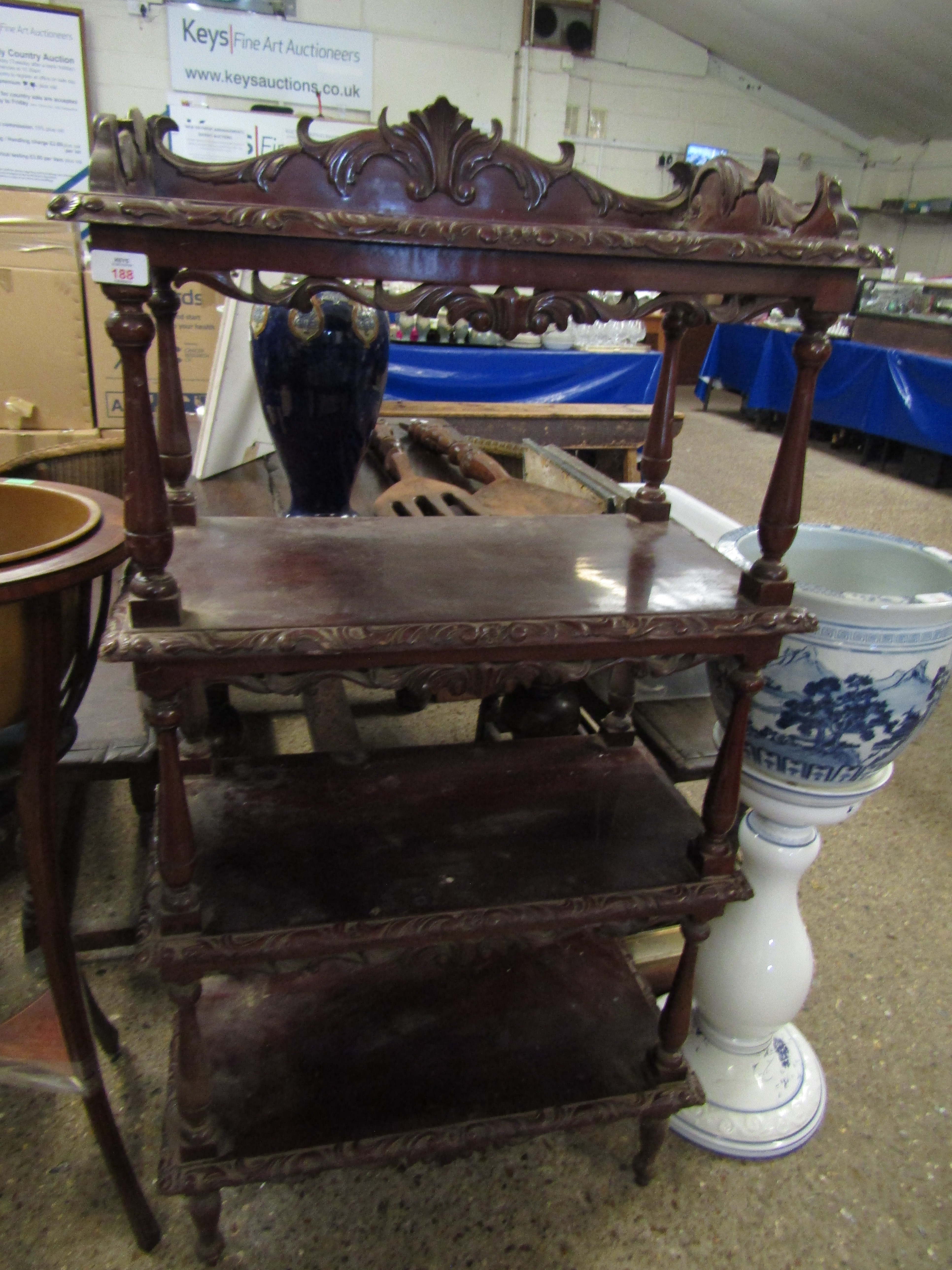 HARDWOOD FOUR TIER WHATNOT WITH HEAVILY CARVED DECORATION ON TURNED COLUMN SUPPORT
