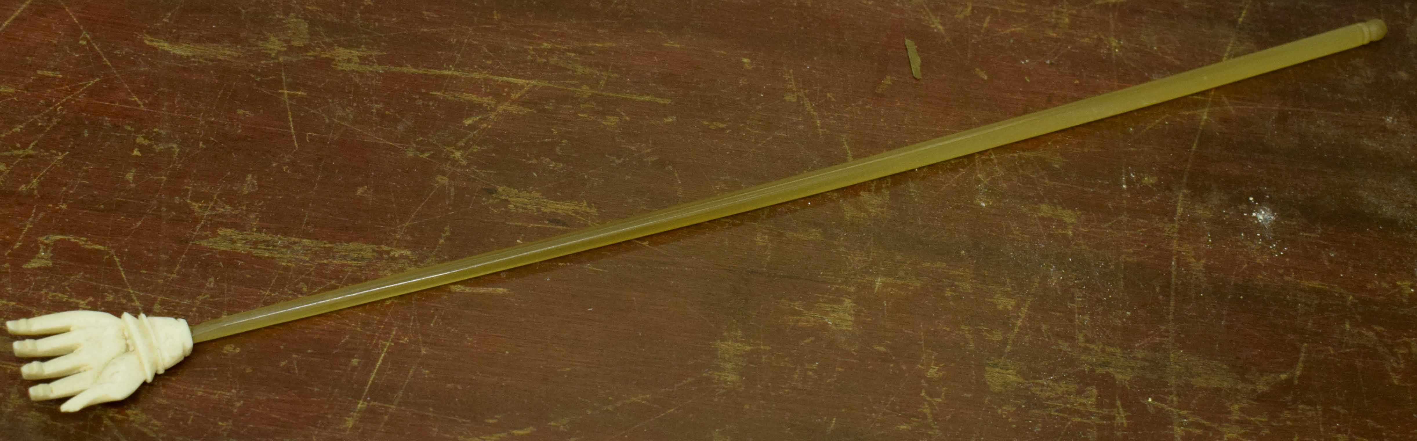 Early 20th century back-scratcher modelled as an ivory hand mounted on a long tube, 39cm long