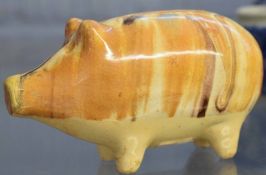 English pottery money box modelled as a pig, decorated with a Whealden type glaze on four stub feet,