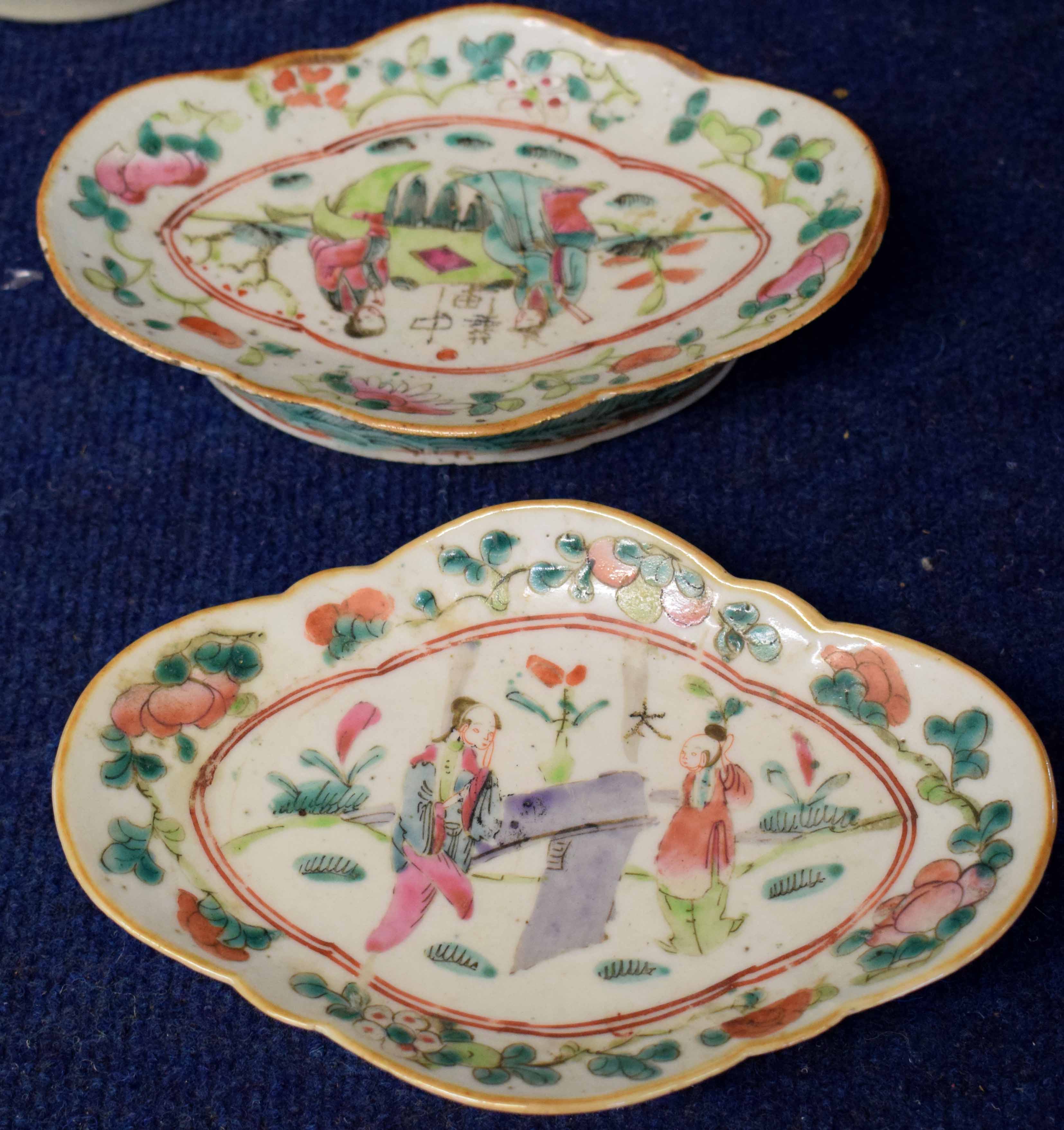 Two shaped Chinese porcelain dishes with polychrome design of figures beside a table, the border