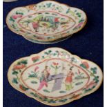 Two shaped Chinese porcelain dishes with polychrome design of figures beside a table, the border